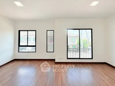 Spacious empty room with large windows and wooden flooring, perfect for customization.