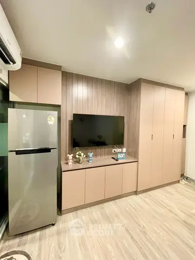 Modern living room with sleek cabinetry and stainless steel fridge, perfect for contemporary living.