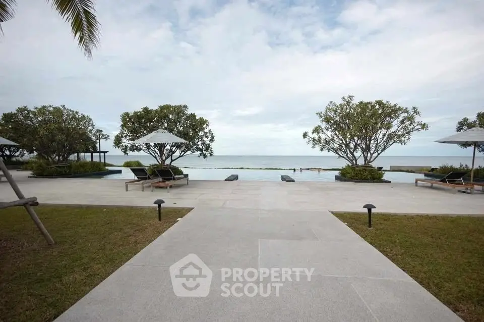 Luxurious beachfront pool area with stunning ocean view and lush greenery.