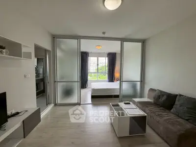 Modern apartment with open layout featuring a cozy living room and bedroom separated by sliding glass doors.