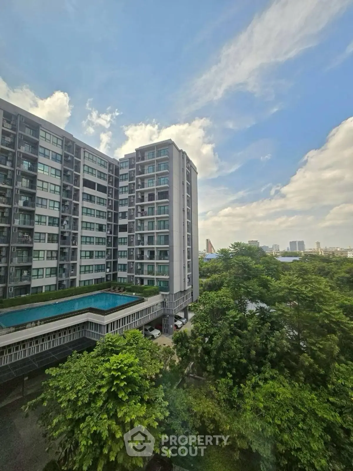 Modern high-rise building with lush greenery and city skyline view