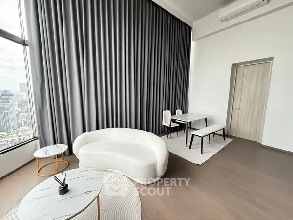 Luxurious modern living room with city view, featuring elegant furniture and floor-to-ceiling windows.