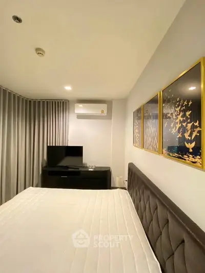 Modern bedroom with elegant decor and wall art, featuring a comfortable bed and sleek TV setup.