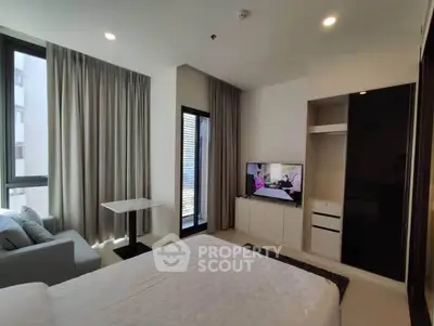 Modern bedroom with large windows and sleek furniture in a contemporary apartment.