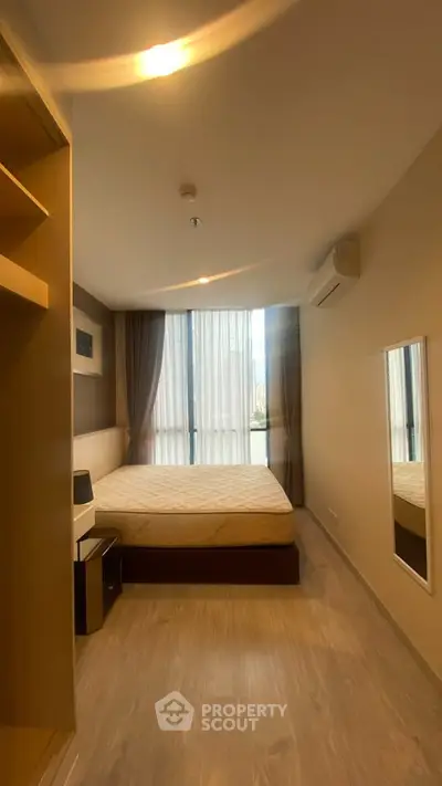 Modern bedroom with large window and stylish decor in a cozy apartment.