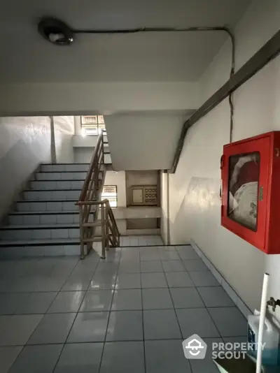 Stairwell in residential building with emergency equipment and tiled flooring