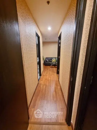 Elegant hallway with wooden flooring leading to a cozy living area with a sofa and decor.