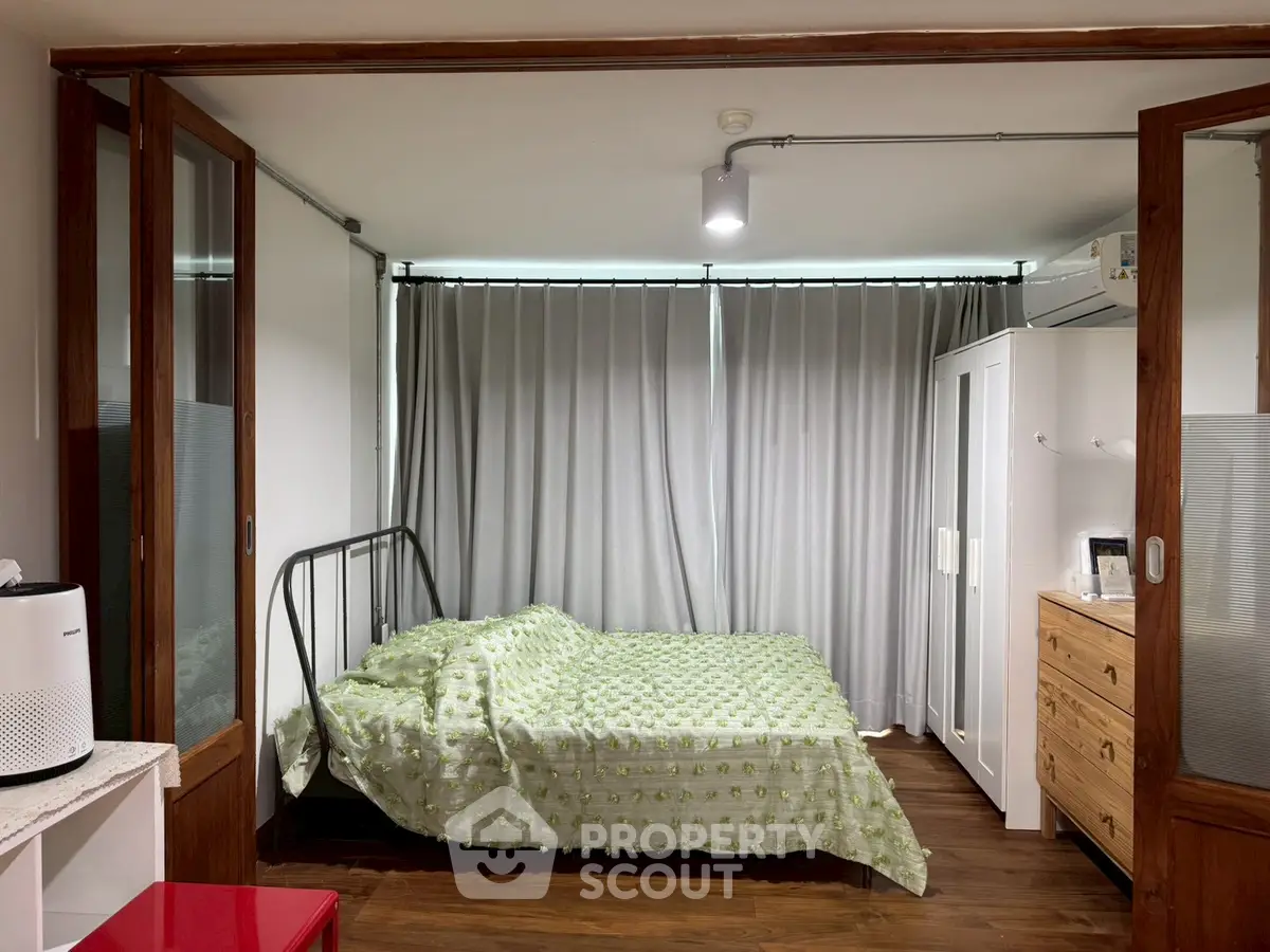 Cozy bedroom with modern decor and ample natural light, featuring a stylish bed and wooden flooring.