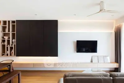 Modern living room with sleek furniture and wall-mounted TV, featuring elegant wooden accents and ample natural light.