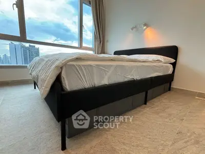 Spacious bedroom with modern bed and stunning city view from large window.