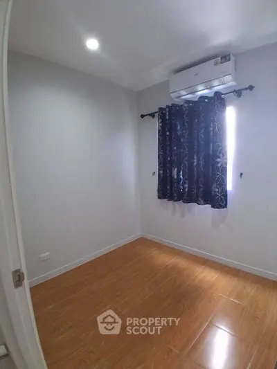 Cozy unfurnished bedroom with air conditioning and wooden flooring, perfect for personalization.