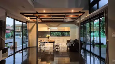 Spacious modern living room with open kitchen and large windows offering garden views.