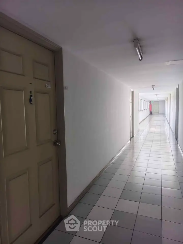 Spacious apartment corridor with tiled flooring and multiple doors, ideal for modern living.