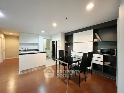 Modern open-layout kitchen and dining area with sleek black and white furniture.