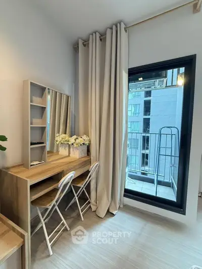 Modern study nook with desk and chairs next to a window overlooking a balcony in a stylish apartment.