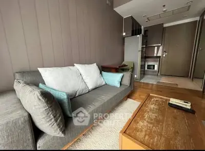 Modern living room with cozy sofa and open kitchen layout in stylish apartment.