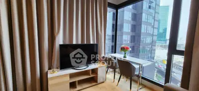 Modern living room with city view, featuring sleek TV setup and elegant dining area by large windows.