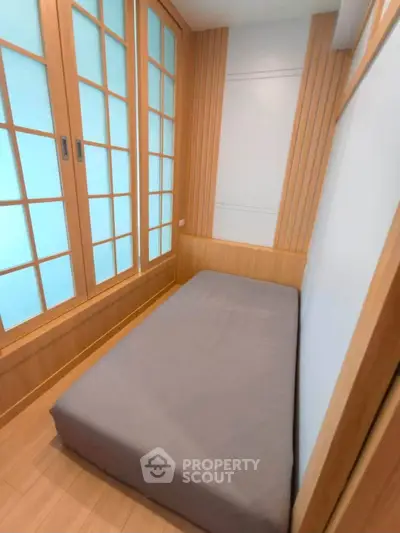 Cozy minimalist bedroom with wooden accents and frosted glass sliding doors.