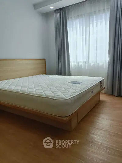 Spacious bedroom with natural light and modern wooden flooring