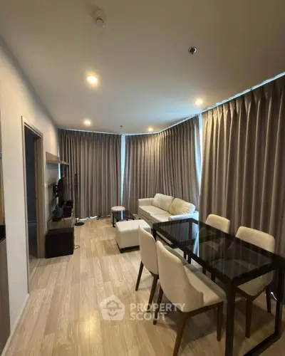 Modern living room with elegant dining area and cozy seating, featuring floor-to-ceiling curtains and warm lighting.