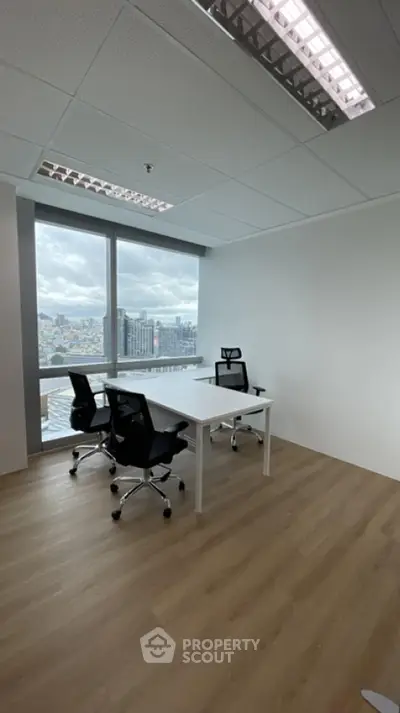 Modern office space with city view, featuring sleek furniture and large windows for natural light.