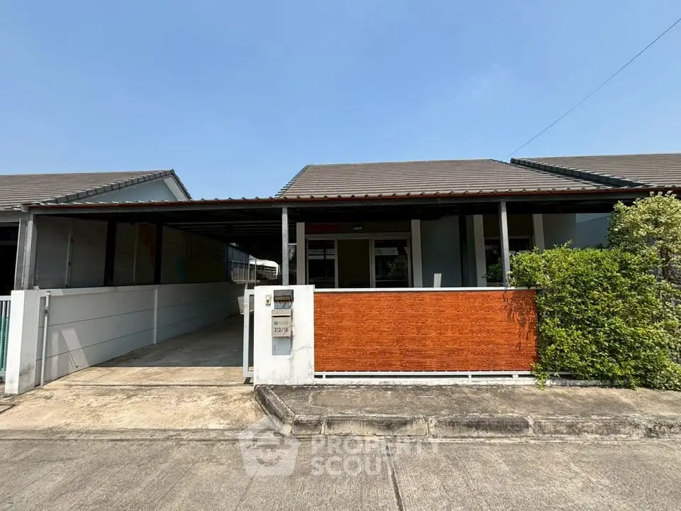Charming single-story house with a covered carport and lush greenery, perfect for family living.