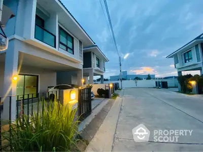 Modern two-story house with driveway and garage in a serene neighborhood at dusk.