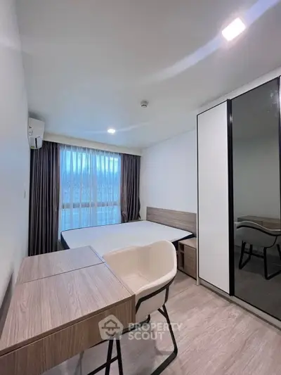 Modern bedroom with sleek furniture and large window offering natural light