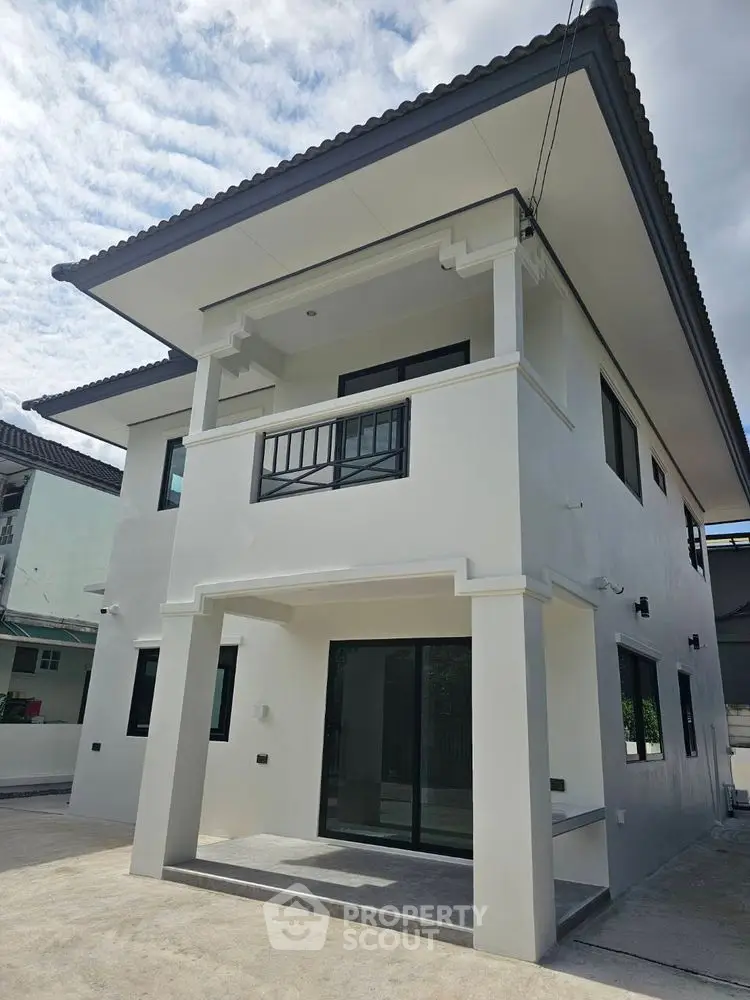 Modern two-story house with sleek design and large windows in a suburban neighborhood.