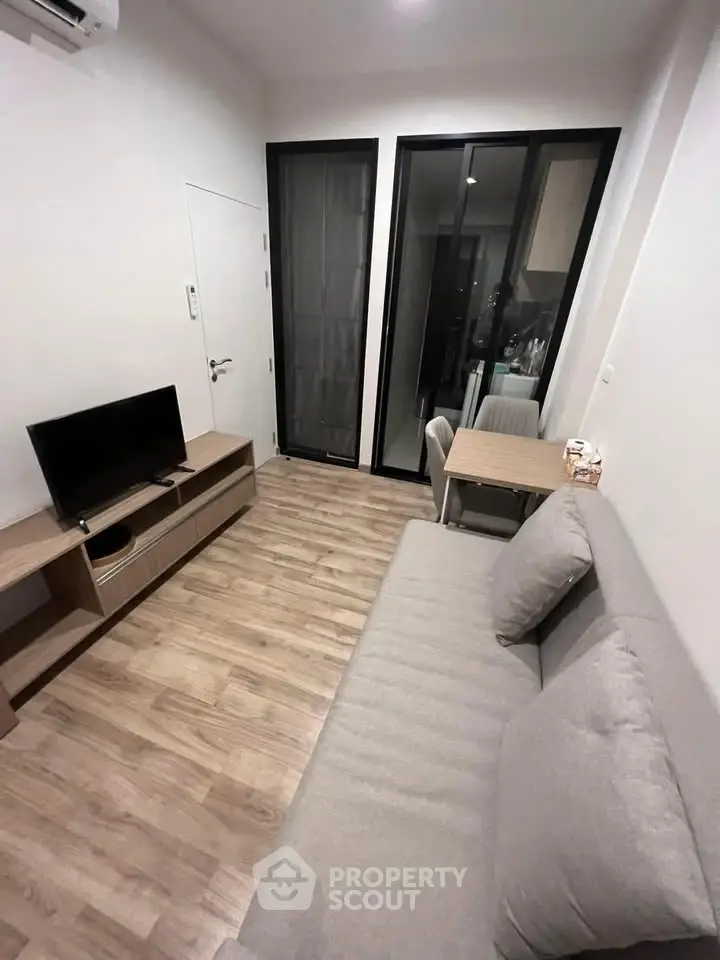 Modern living room with sleek furniture and open layout, featuring a cozy sofa and entertainment unit.