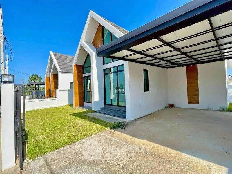 Modern single-story house with sleek design and spacious carport, featuring large windows and a lush green lawn.