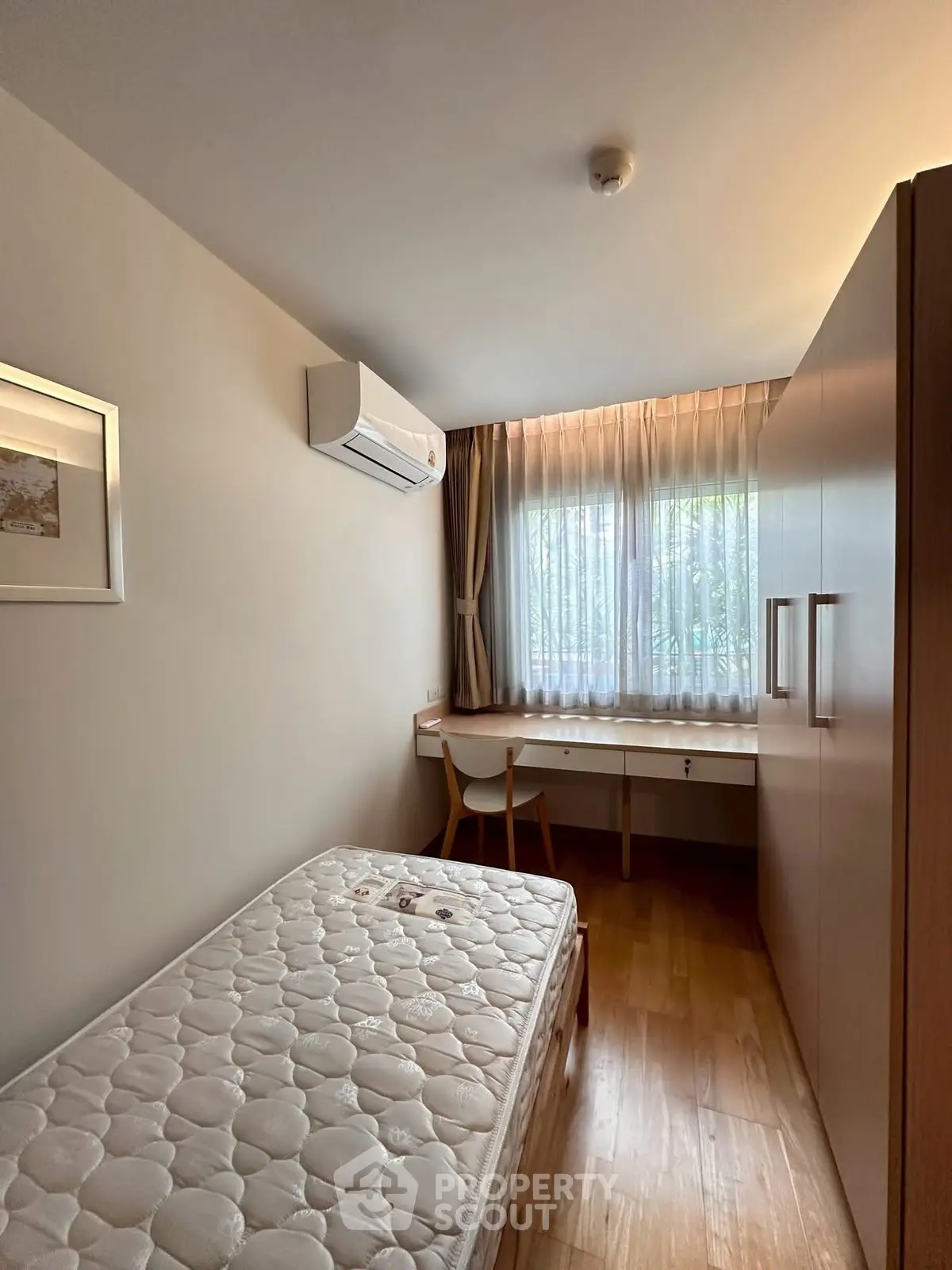 Cozy bedroom with natural light, featuring a single bed, desk, and ample storage space.