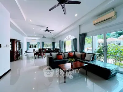 Spacious living room with modern furniture and large windows offering garden views.