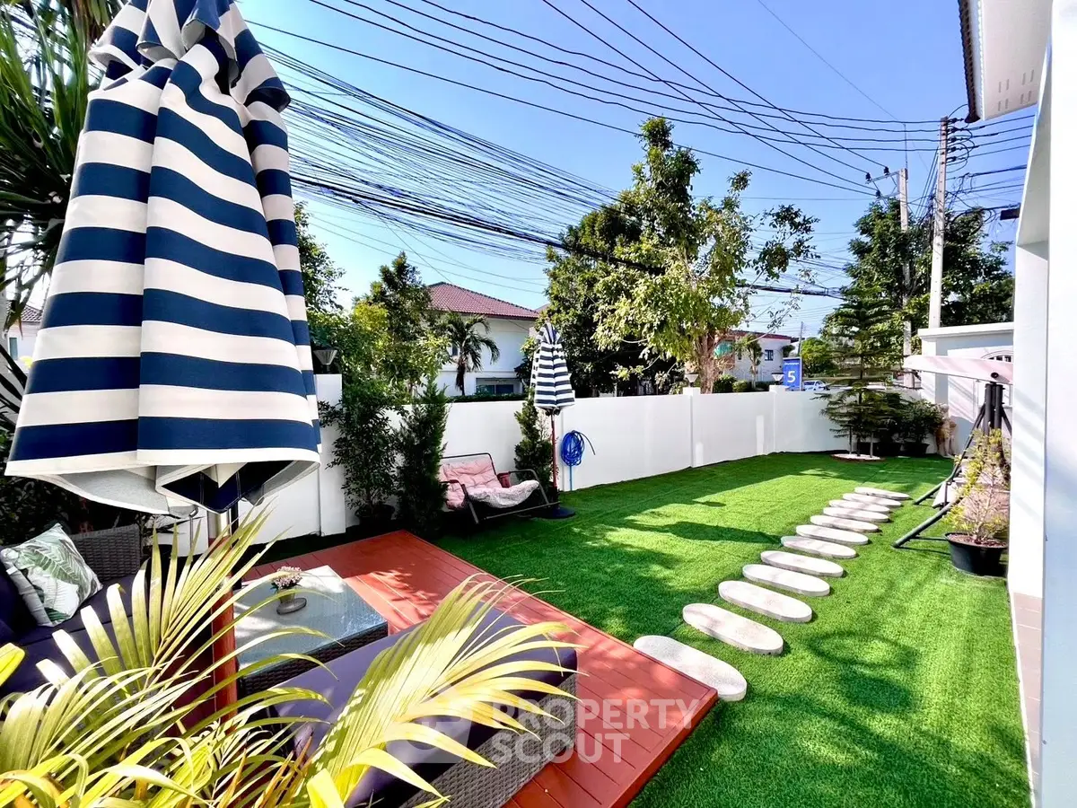 Charming backyard with lush garden, cozy seating, and vibrant greenery, perfect for outdoor relaxation.