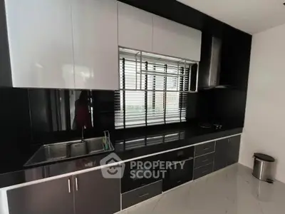Modern kitchen with sleek black and white cabinetry and built-in appliances.