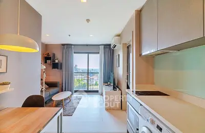 Modern open-plan living room with kitchen, featuring a balcony with city view, stylish decor, and natural light.