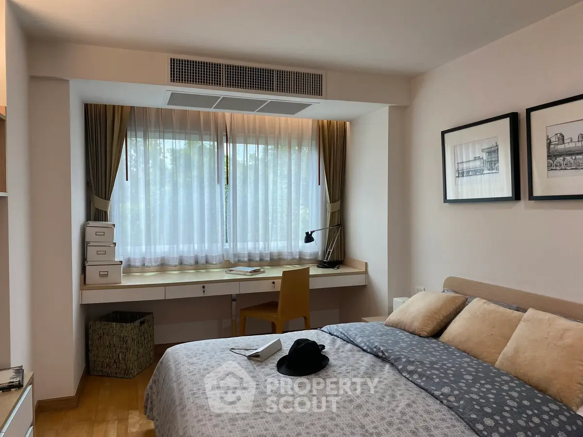Cozy bedroom with a study nook, featuring a large window and elegant decor, perfect for relaxation and productivity.