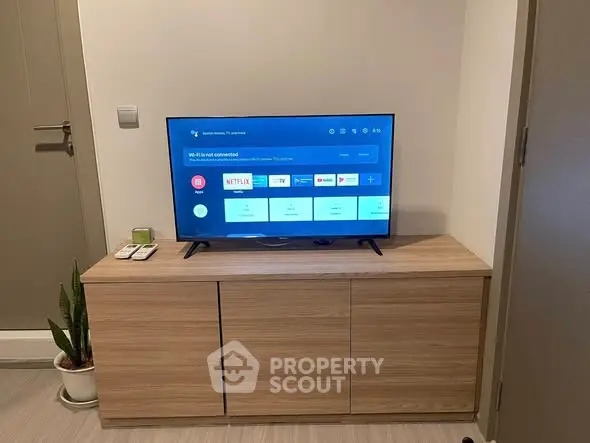 Modern living room with sleek TV setup on wooden cabinet, perfect for entertainment.