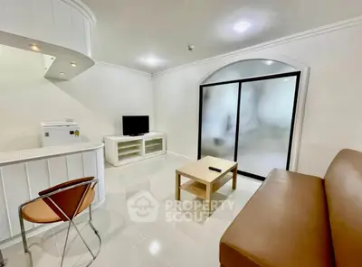 Modern living room with sleek furniture and minimalist design, featuring a TV and sliding glass doors.