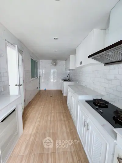 Sleek modern kitchen with gas stove and white cabinetry in a narrow layout.