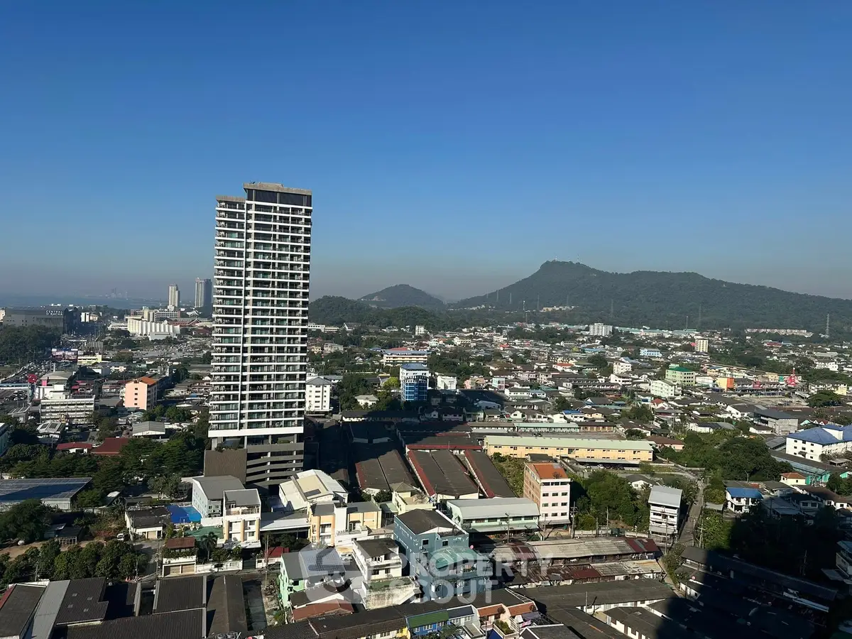 Stunning cityscape view with high-rise building and scenic mountains in the background.