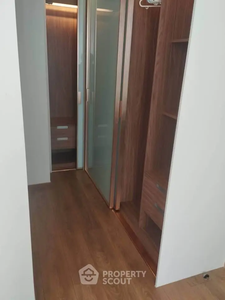 Spacious walk-in closet with wooden flooring and modern sliding doors.