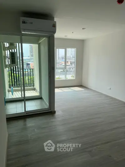 Spacious modern apartment with balcony and city view, featuring sleek flooring and ample natural light.