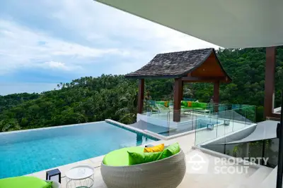 Luxurious villa with infinity pool and stunning ocean view, surrounded by lush greenery.