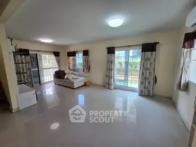 Spacious living room with large windows and plush seating, ideal for family gatherings.