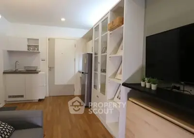 Modern living room with sleek design, featuring built-in shelves, compact kitchen, and cozy seating area.