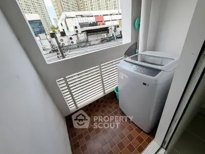 Compact balcony with washing machine and city view, ideal for urban living convenience.