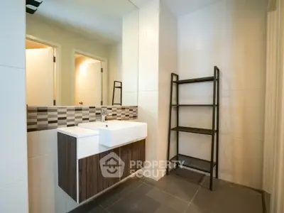 Modern bathroom with stylish sink and shelving unit, featuring sleek tile design.