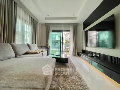 Modern living room with large sofa and wall-mounted TV, featuring elegant decor and natural light.