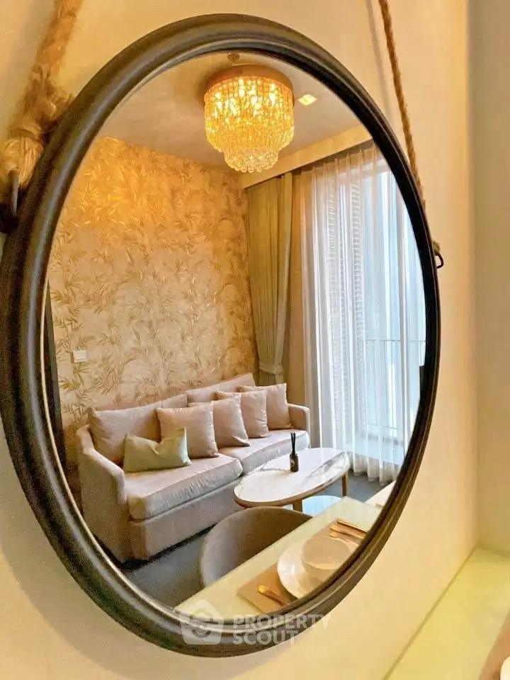Elegant living room with chic decor and chandelier reflected in a round mirror.
